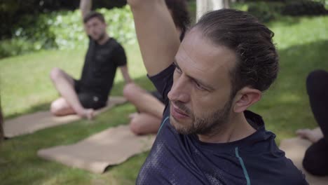 Sporty-flexible-men-practicing-yoga-in-park